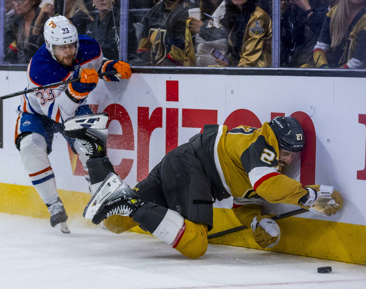 Golden Knights defenseman Shea Theodore (27) smashes into the boards after battling with Edmont ...