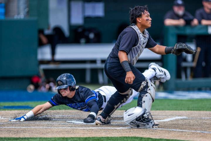 Basic runner Andruw Giles (29) slides home safely past Faith Lutheran catcher Kade Gerboc-Chun ...