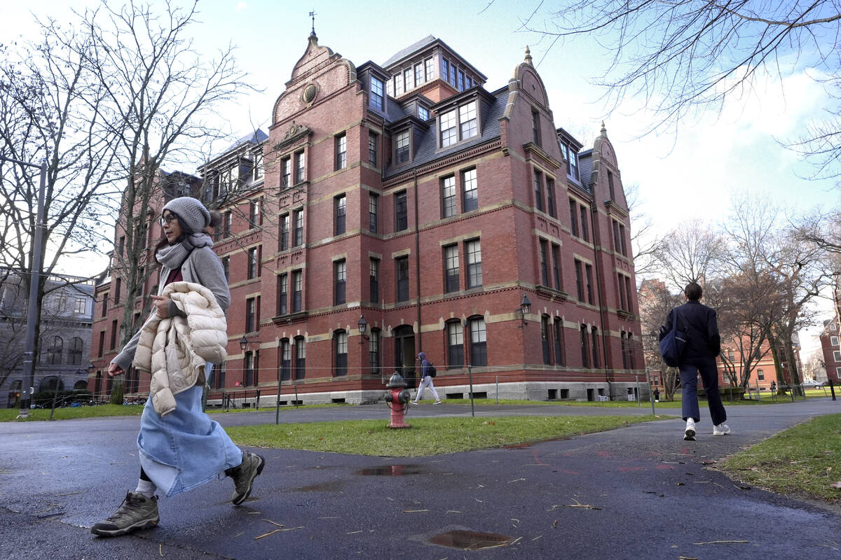 FILE - People walk between buildings, Dec. 17, 2024, on the campus of Harvard University in Cam ...